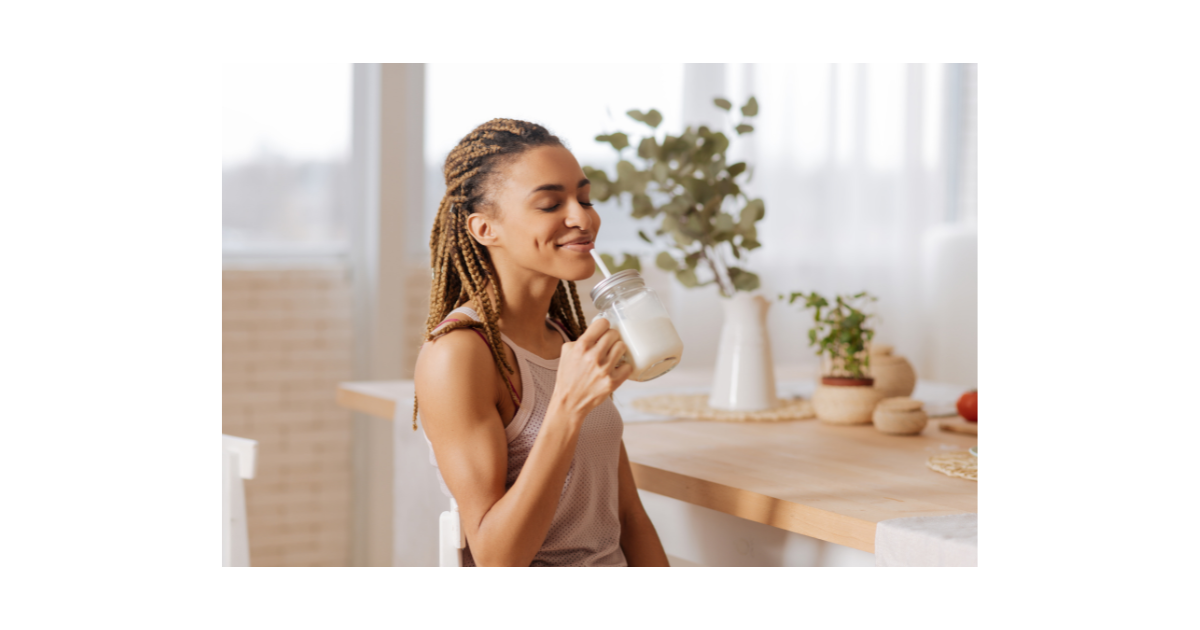 black woman enjoying a smoothie in the kitchen of her home